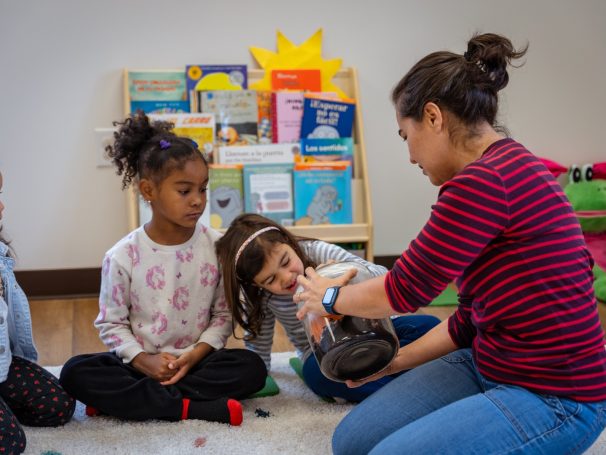 Teacher at spanish preschool in Harrisonburg showing students something in a circle